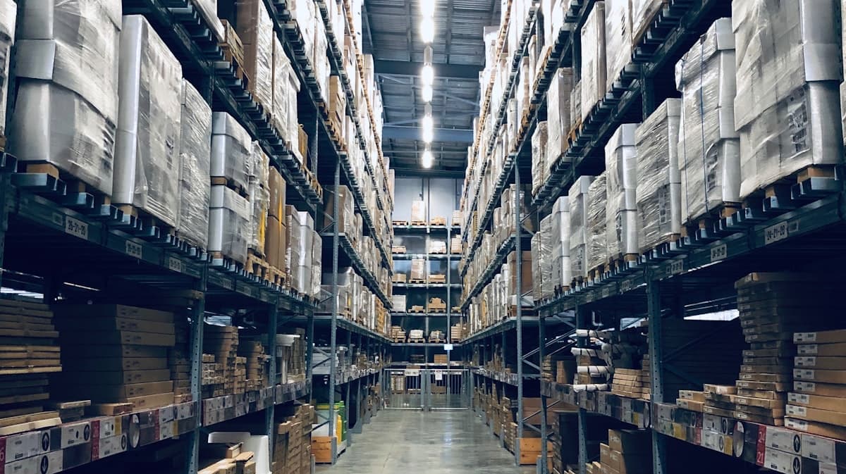 Side-by-side comparison of a small in-house warehouse packing station and a large 3PL fulfillment center with conveyor belts